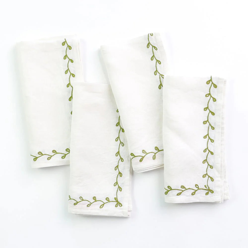 White linen napkins with green embroidered design