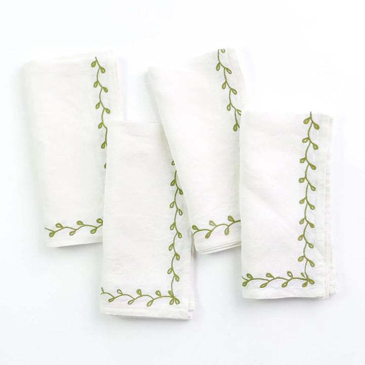White linen napkins with green embroidered design