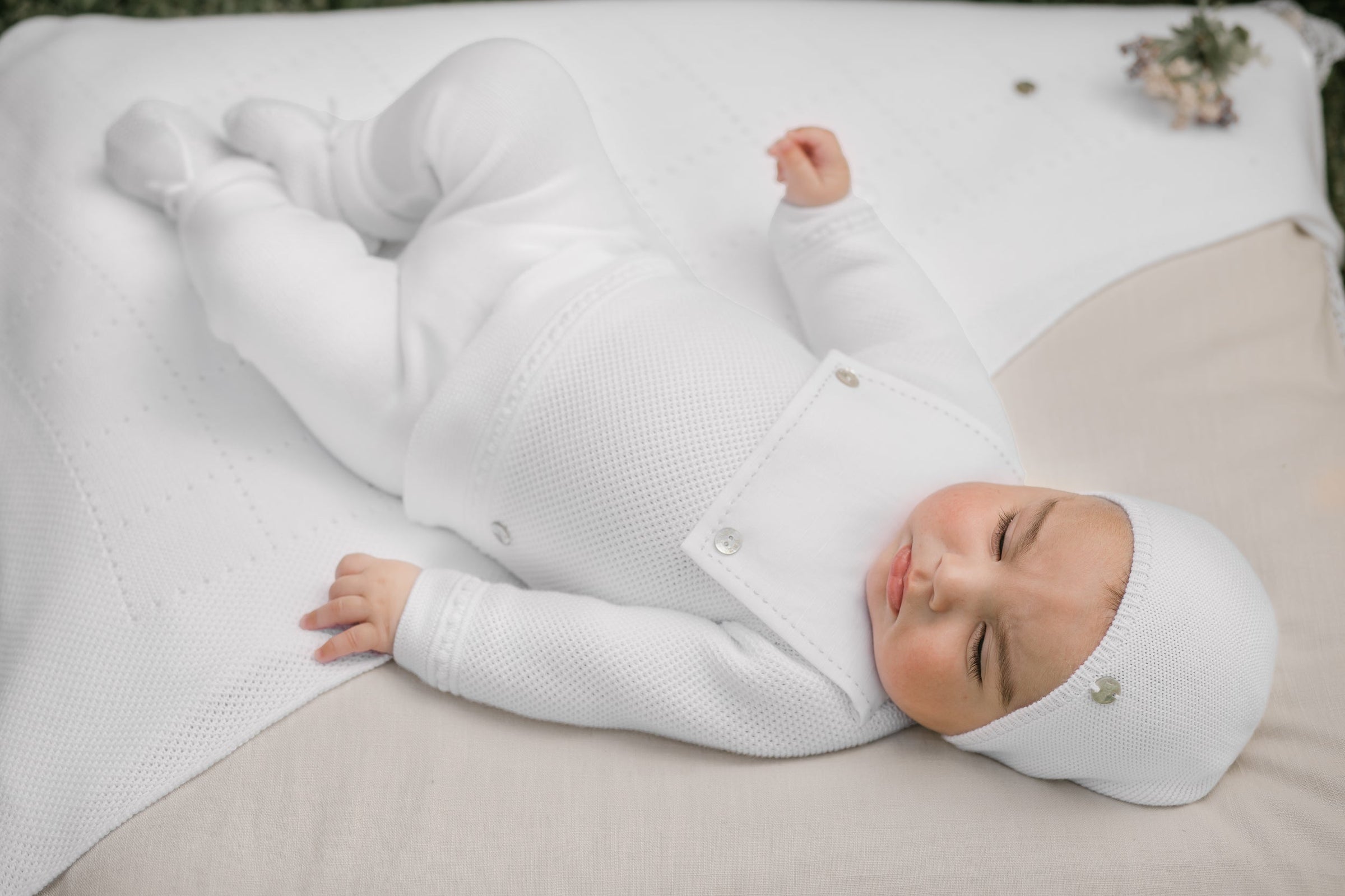 Baby Boy in White outfit laying on blanket outside