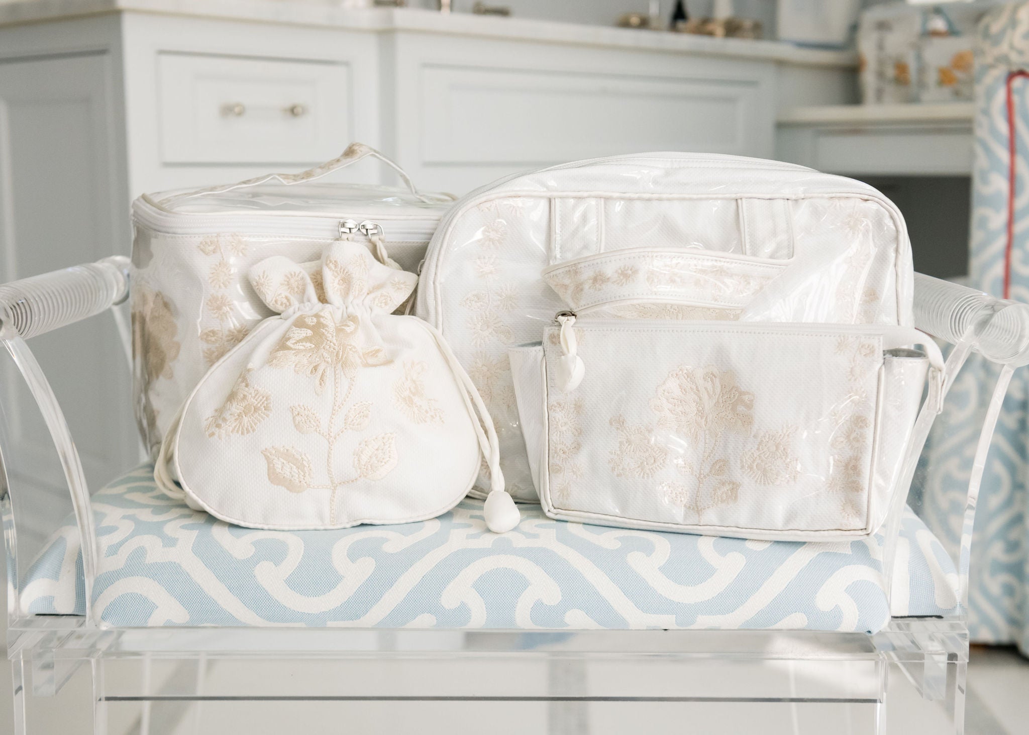 Ivory toiletry bags with embroidered peony sit on top of a decorative bathroom bench