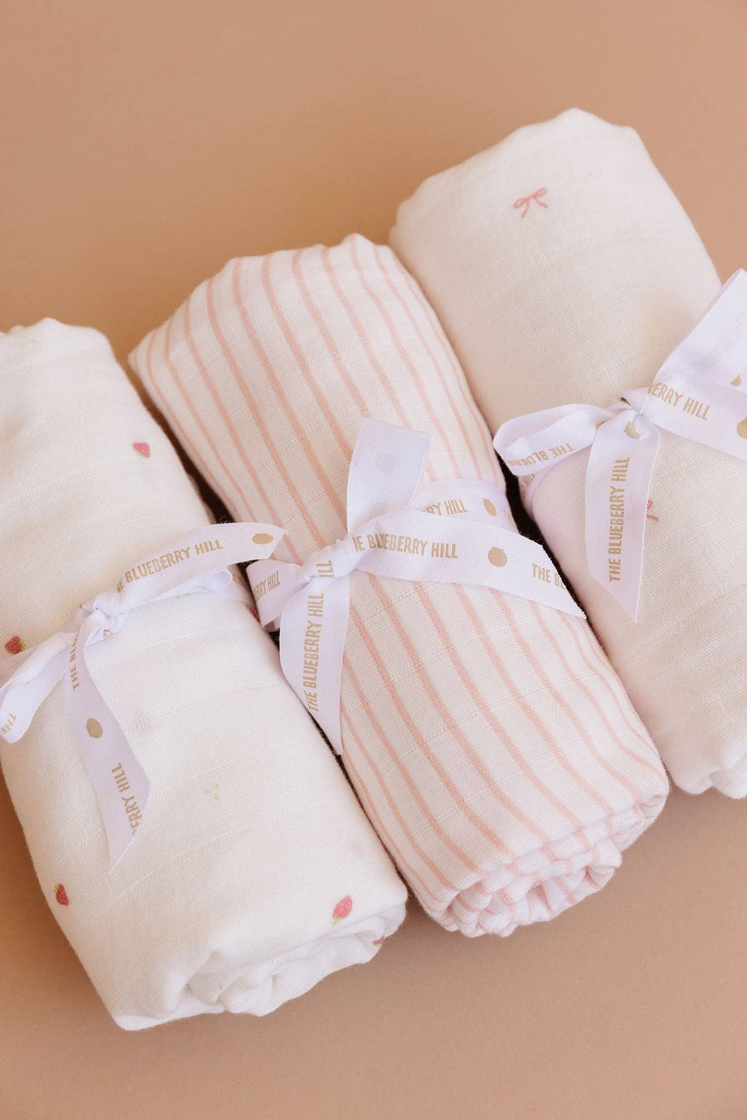 Folded baby blankets with ribbons on a beige background