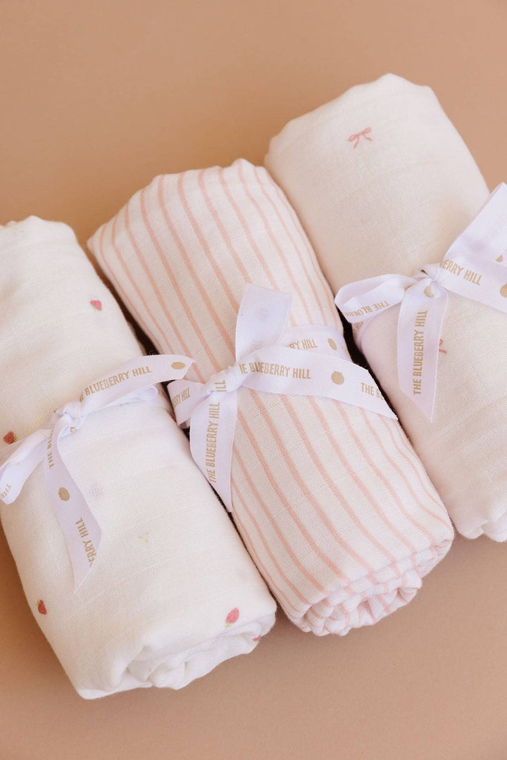 Folded baby blankets with ribbons on a beige background