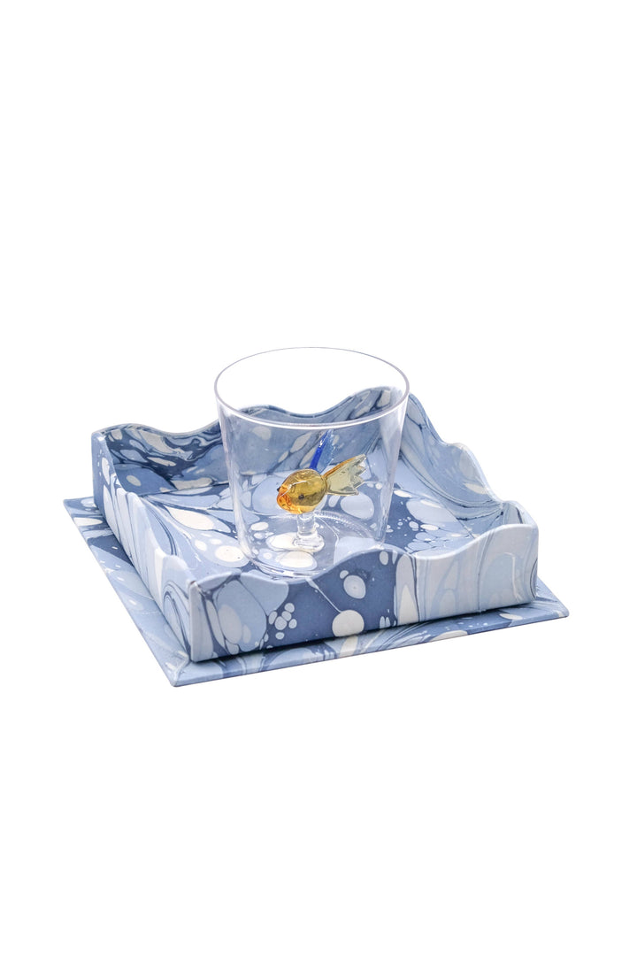 Glass with fish design on a blue and white patterned napkin on a white background