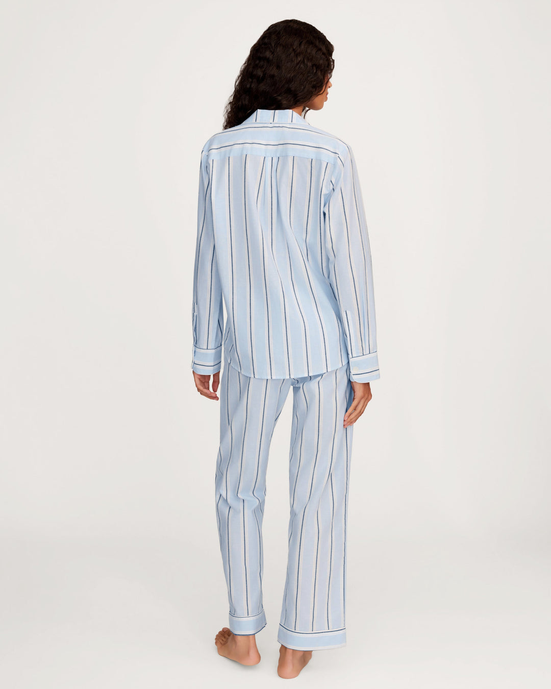 Person wearing a light blue and white striped pajama set on a white background