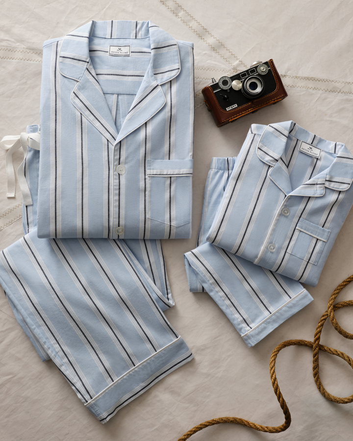 Blue striped pajama set on a beige surface with a vintage camera and rope.
