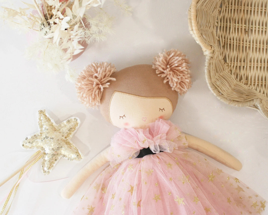 Doll with pink dress and pom-pom hair on a light background
