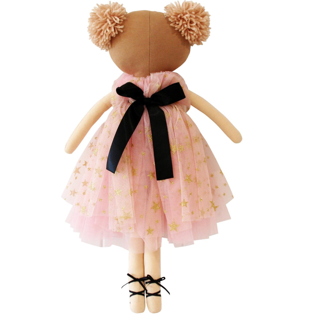Stuffed toy bear wearing a pink dress with gold stars and a black bow on a white background