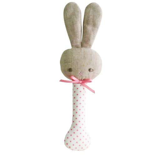 Textured bunny rattle with pink polka dot handle on a white background