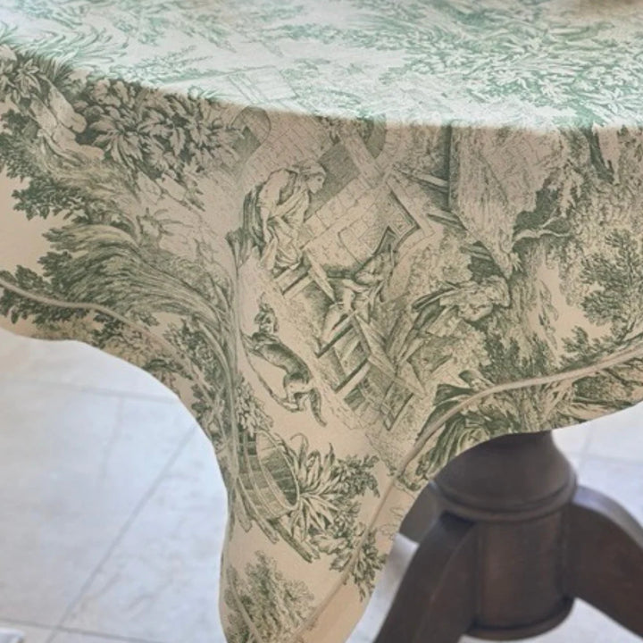 Close-up of a patterned tablecloth with green and beige design on a wooden table.