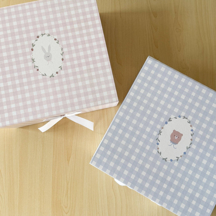 Two checkered boxes with embroidered designs on a wooden surface