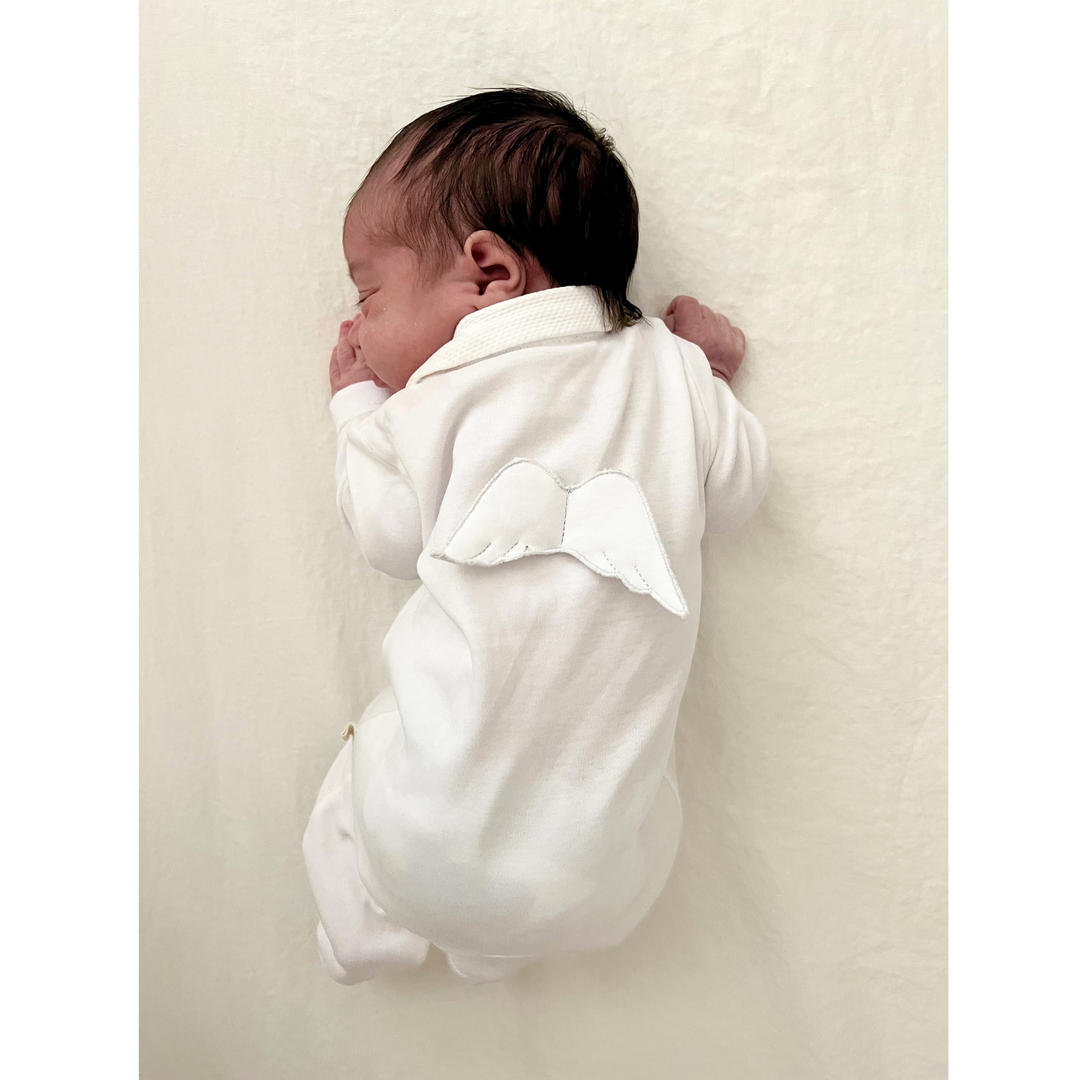 newborn baby wearing white footie with angel wings