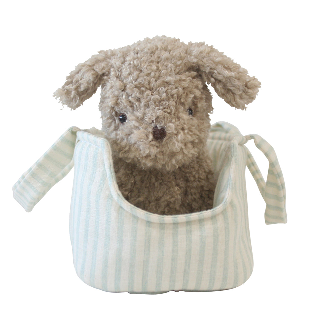 Stuffed dog toy inside a striped bag on a white background