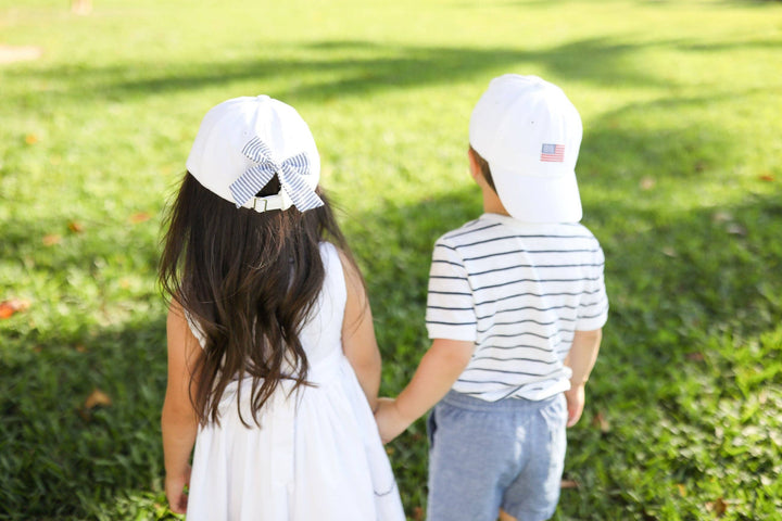 Two children wearing patriotic baseball caps outside