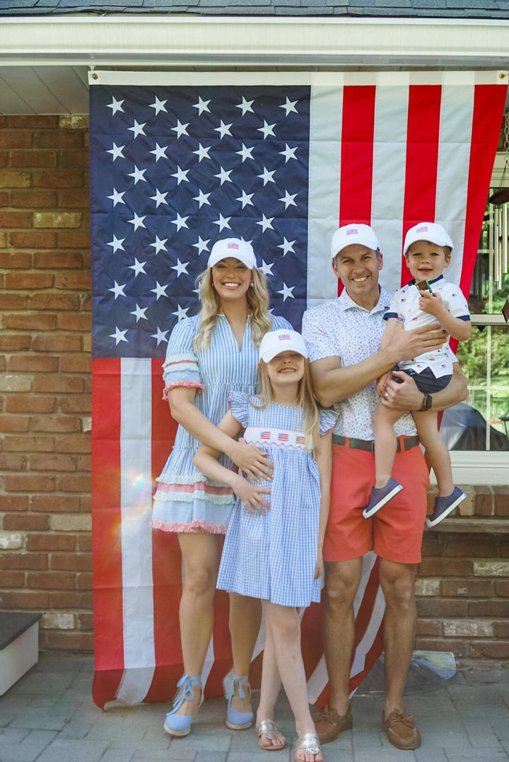Family of four posing in front of a large American flag