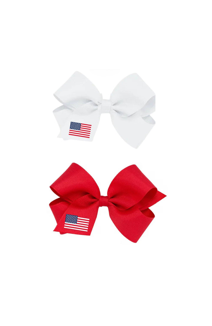 Two hair bows, one white and one red, each with an American flag patch on a white background.