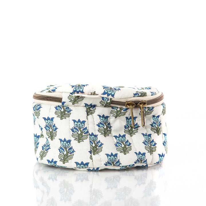A small quilted cosmetic pouch with a blue and green floral block print on a white background, featuring a gold-tone zipper.