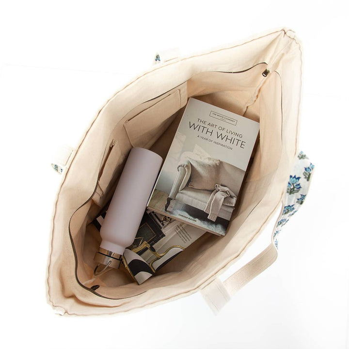 Beige tote bag with a book and a bottle on a white background