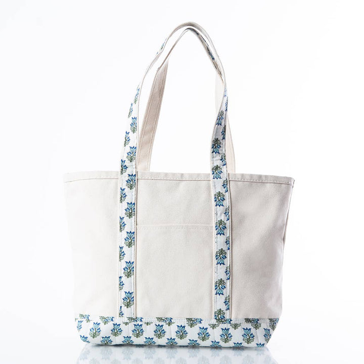 An off-white canvas tote bag with blue and green floral patterned straps and bottom trim, shown on a clean white background.