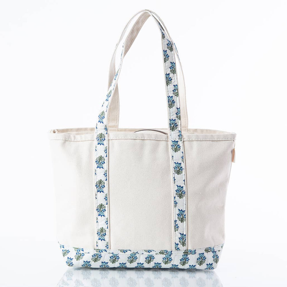 An off-white canvas tote bag with blue and green floral patterned straps and bottom trim, shown on a clean white background.