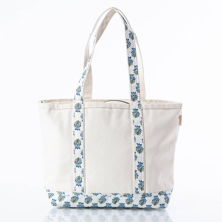 An off-white canvas tote bag with blue and green floral patterned straps and bottom trim, shown on a clean white background.