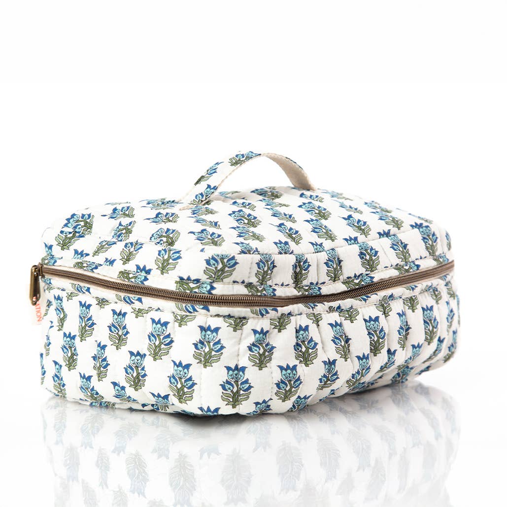 A quilted travel or toiletry bag with a blue and green floral block print on a white background, featuring a top handle and a brown zipper.