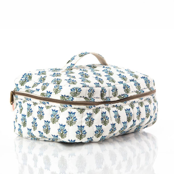 A quilted travel or toiletry bag with a blue and green floral block print on a white background, featuring a top handle and a brown zipper.