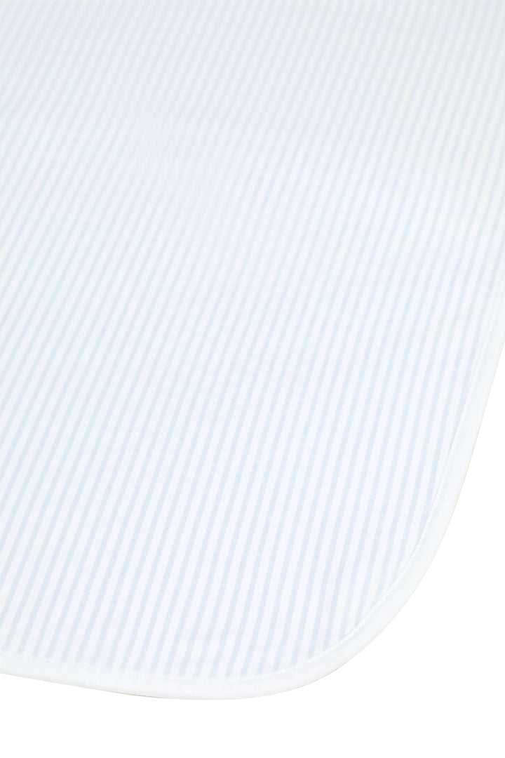 A close-up of a white textured fabric with fine vertical stripes and a rounded corner, likely a baby blanket or swaddle.