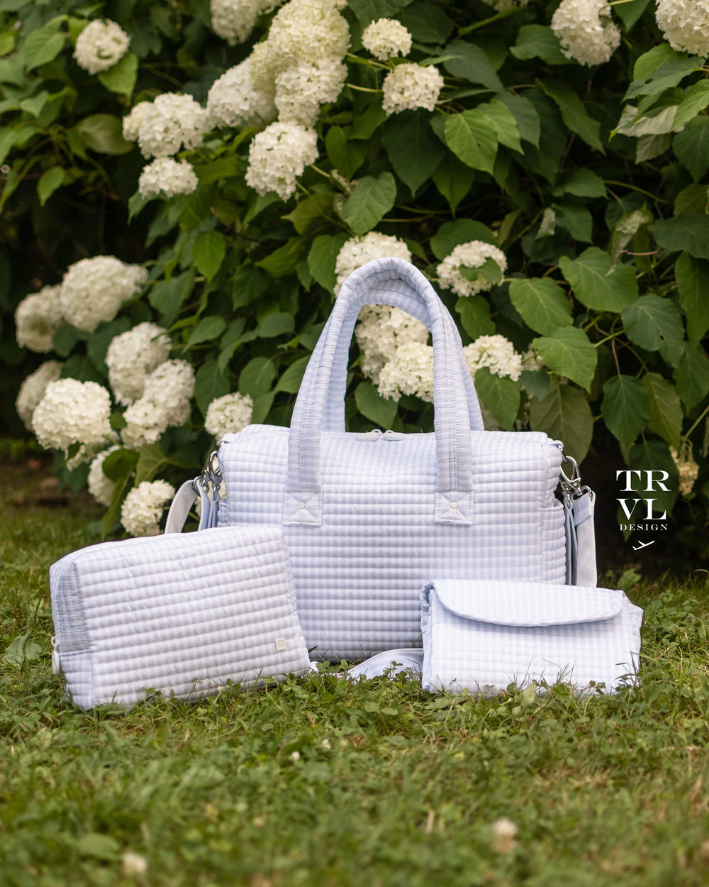 Set of baby bags in front of greenery and white hydrangeas