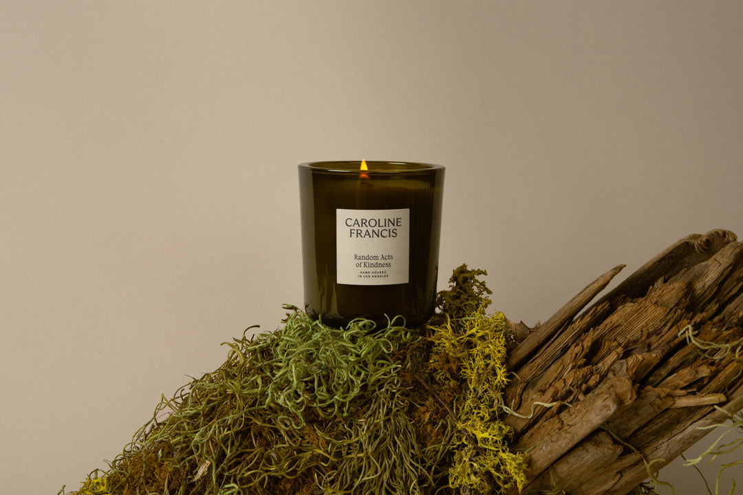 Candle with 'Caroline Francis' branding on a natural background