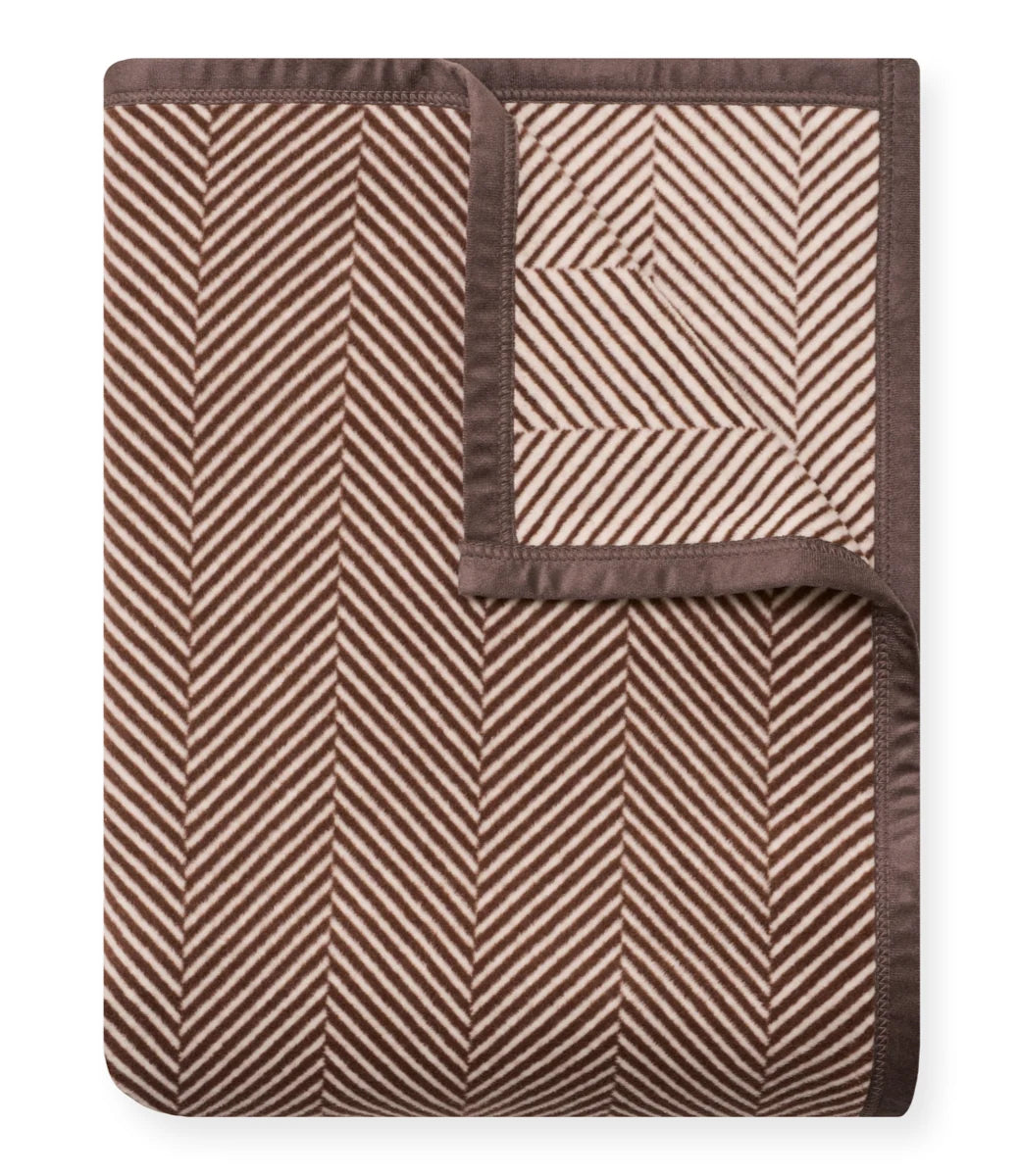Brown and beige herringbone patterned blanket on a white background