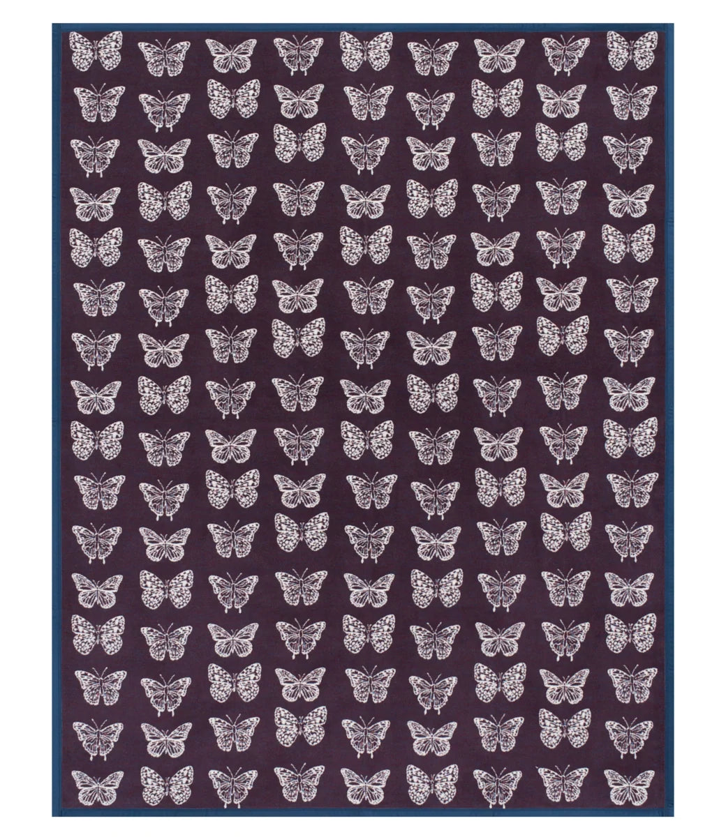 A rectangular rug featuring a repeating pattern of white butterflies on a dark plum-purple background, finished with a solid dark blue border.