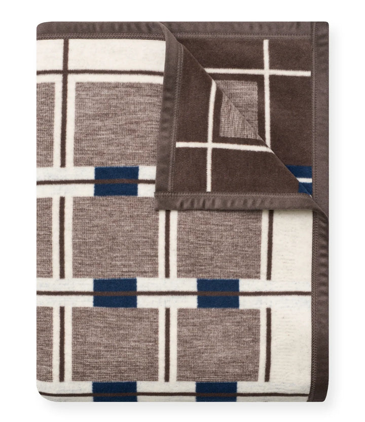 A folded knit blanket with a geometric plaid pattern in brown, cream, and navy blue, shown on a clean white background.