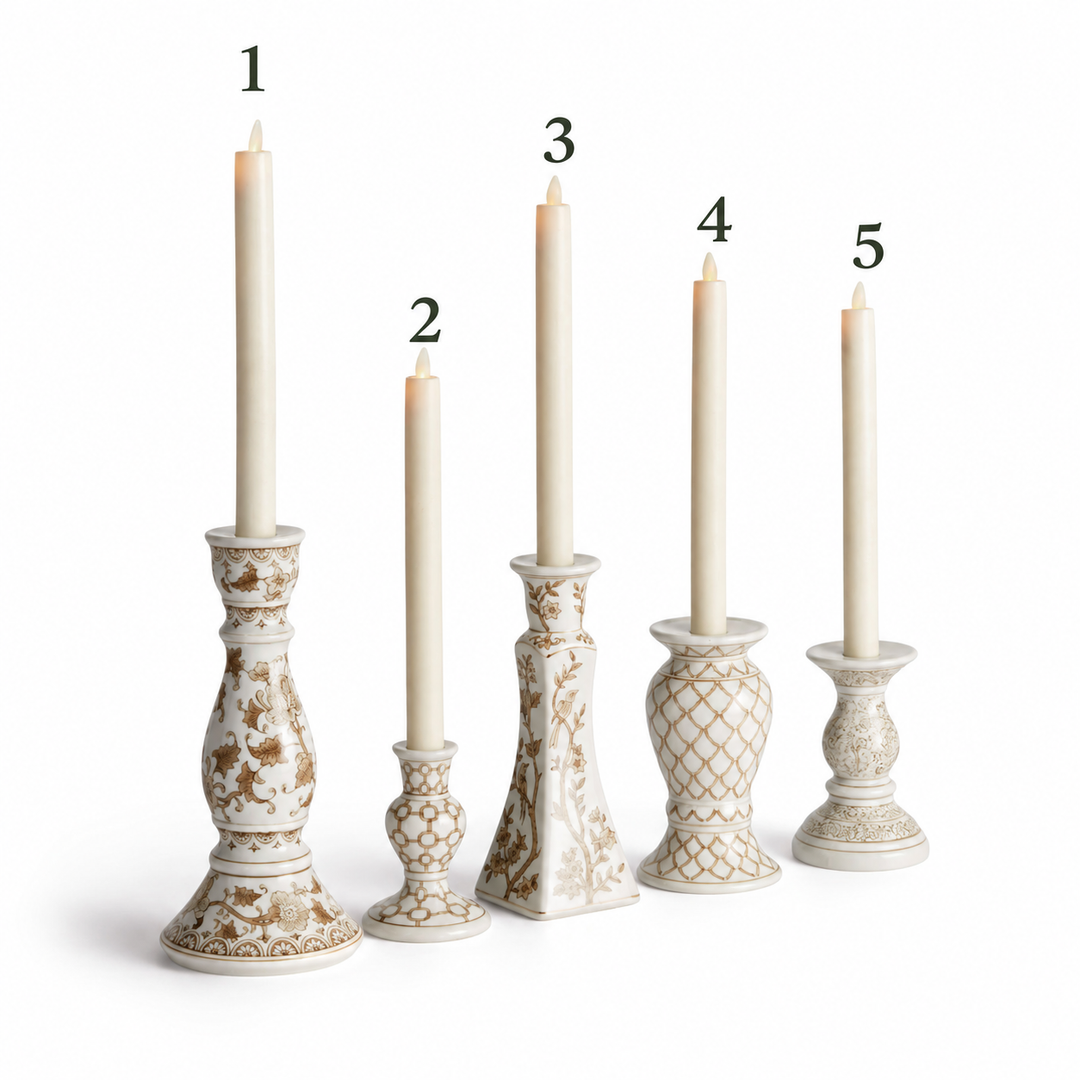 Five cream-colored ceramic candlestick holders with gold floral patterns, arranged in a row from tallest to shortest, each holding a matching cream taper candle. The holders feature different ornate designs, and the candle heights are numbered 1 through 5.