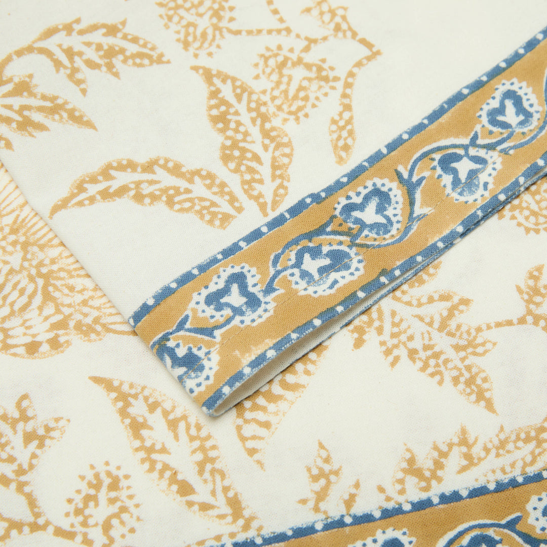 Close-up of a fabric with gold and blue pattern on a white background