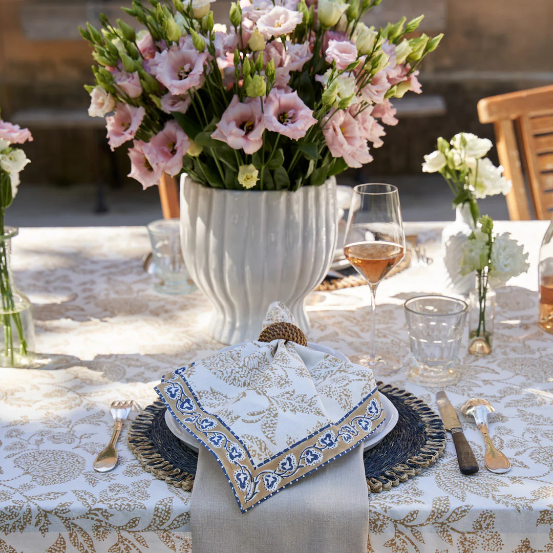 Elegant table setting with floral arrangements, glasses, and cutlery on a patterned tablecloth.