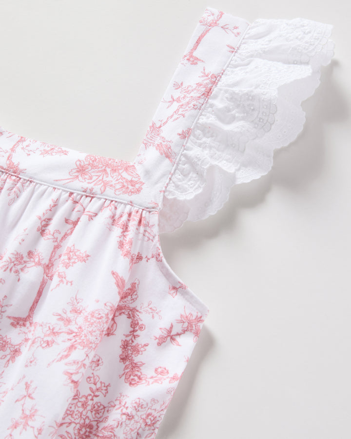 White dress with pink floral pattern and ruffled neckline on a light gray background