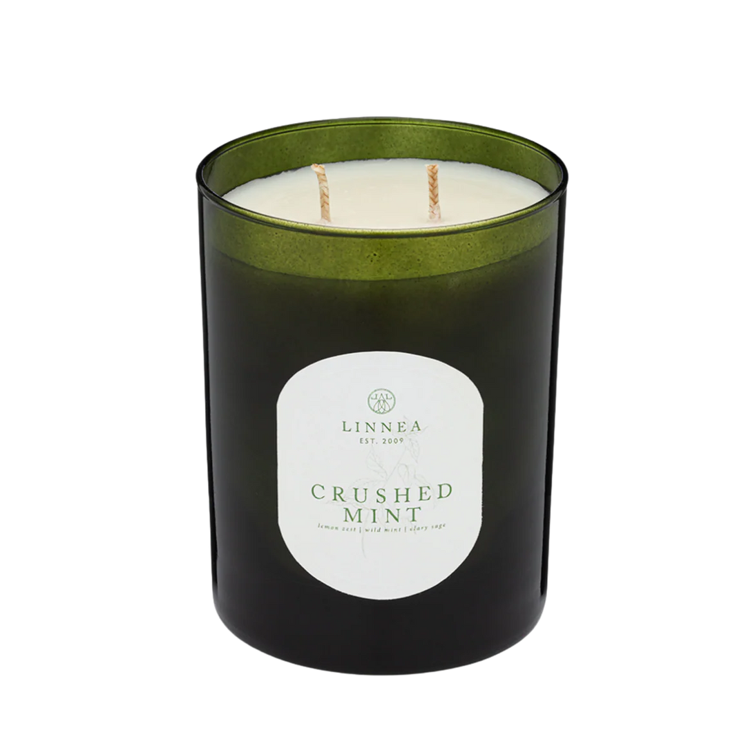 Black candle with green lid and 'Linnea' label on a white background