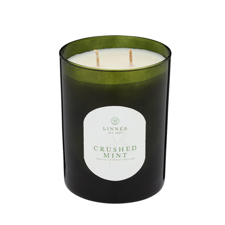 Black candle with green lid and 'Linnea' label on a white background