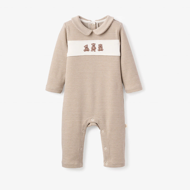A baby long-sleeve romper in beige and white waffle knit, featuring a Peter Pan collar, a white chest panel with three embroidered teddy bears, and snap closures at the crotch.