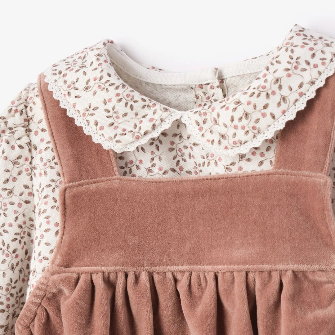 Children's outfit with pink pinafore and floral blouse on a white background