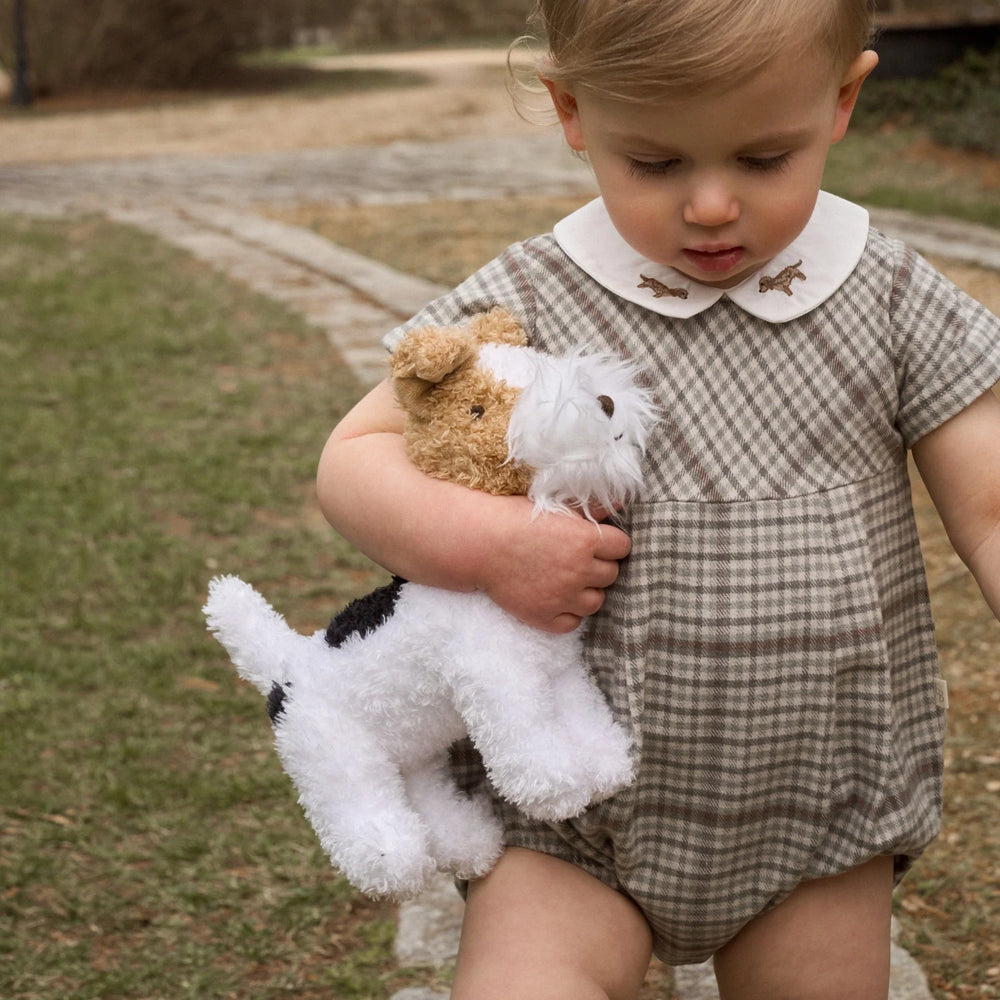 Child holding a stuffed dog toy outdoors
