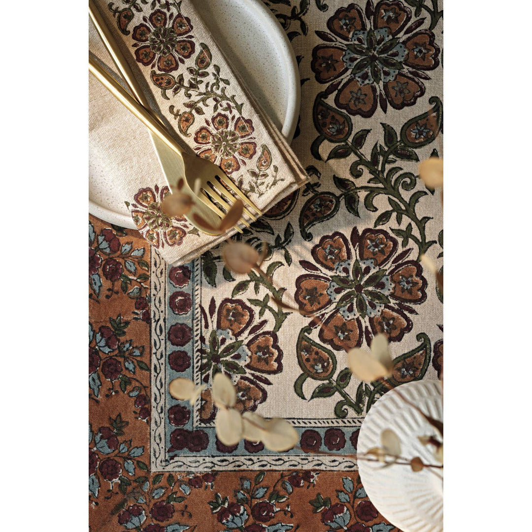 Decorative table setting with floral patterned placemat, napkin, and cutlery.