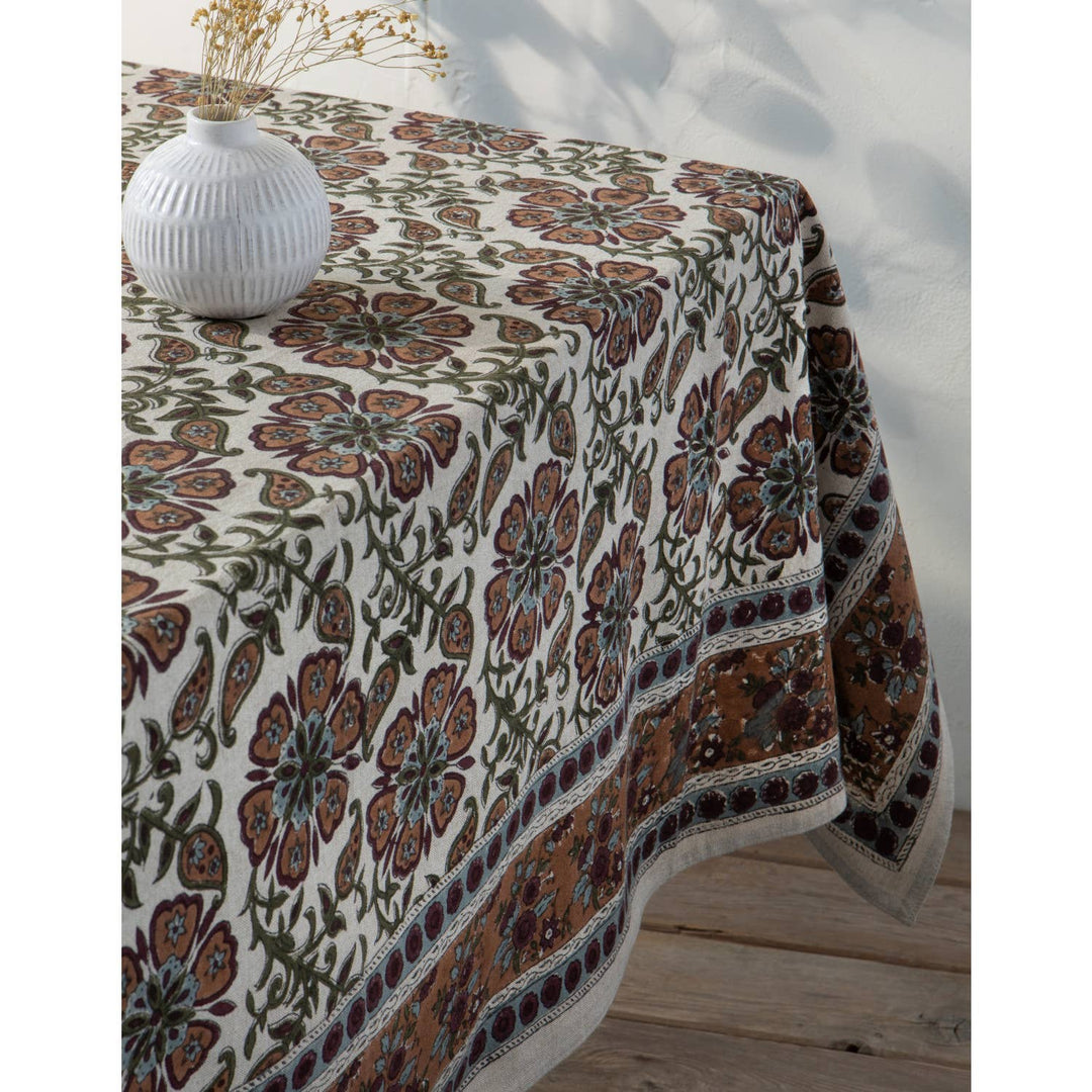 Floral patterned tablecloth on a wooden table with a vase.