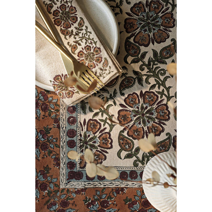 Decorative table setting with floral patterned placemat, napkin, and cutlery.