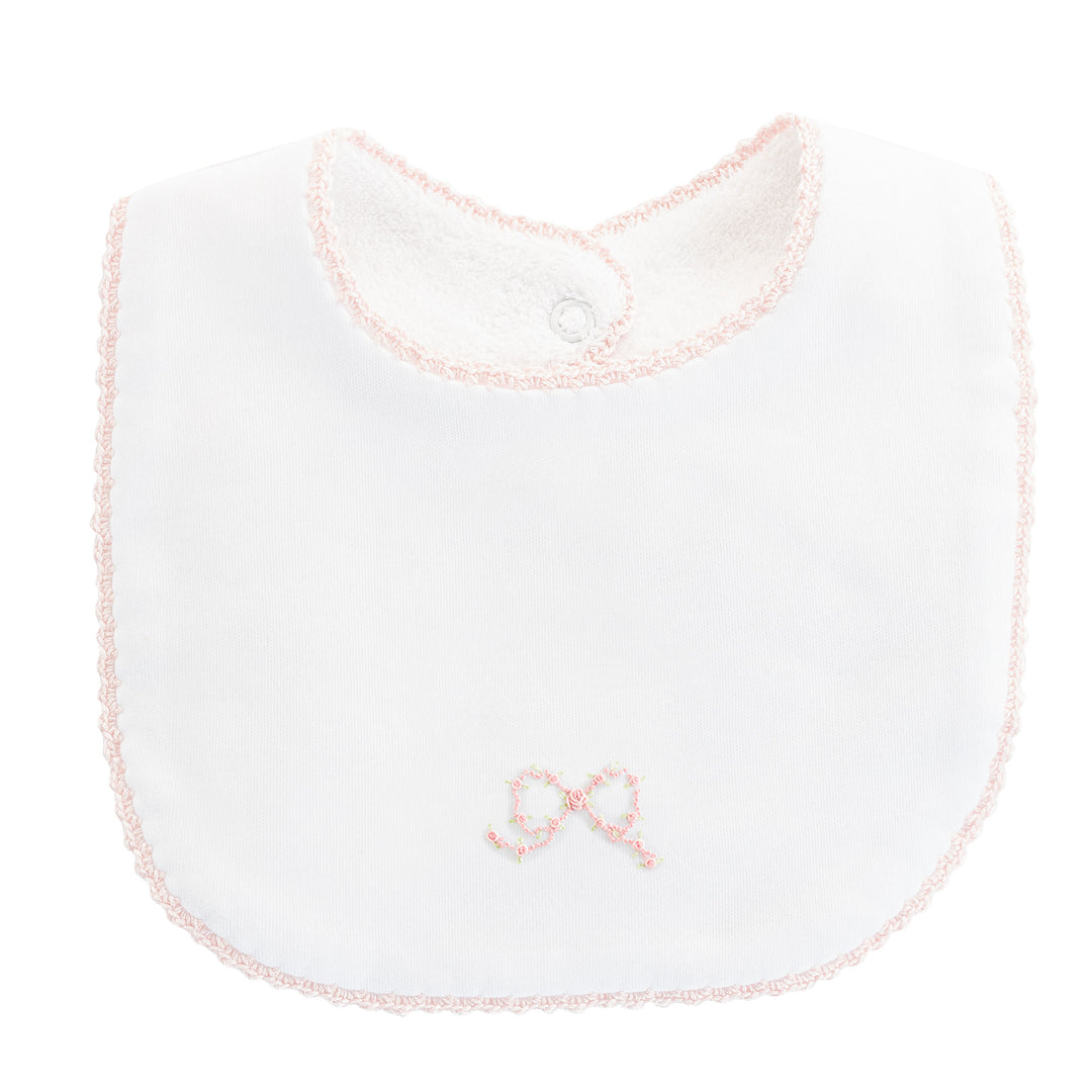 A white baby bib with a light pink embroidered bow on the front and a matching pink scalloped trim around the edges and neckline.