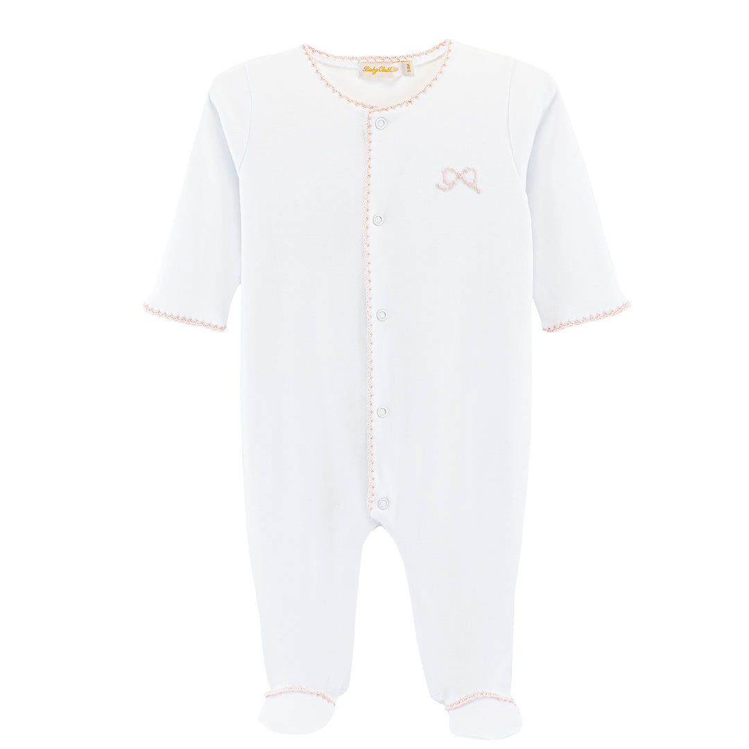 A white baby footed sleeper with long sleeves, snap-button front, and delicate pink trim details, shown on a plain white background.