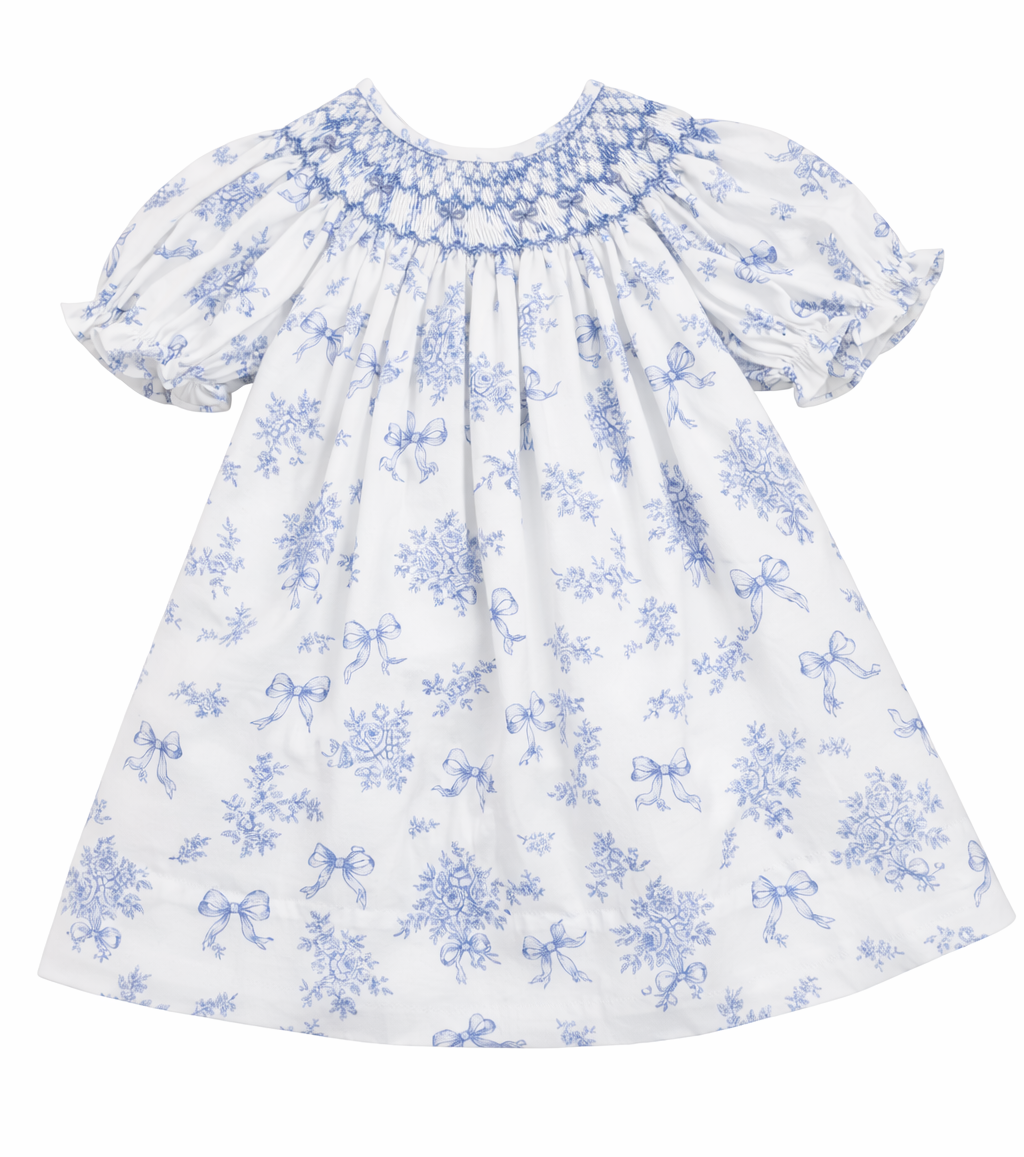 White bishop smocked baby dress with blue toile floral and bow print and puffed sleeves
