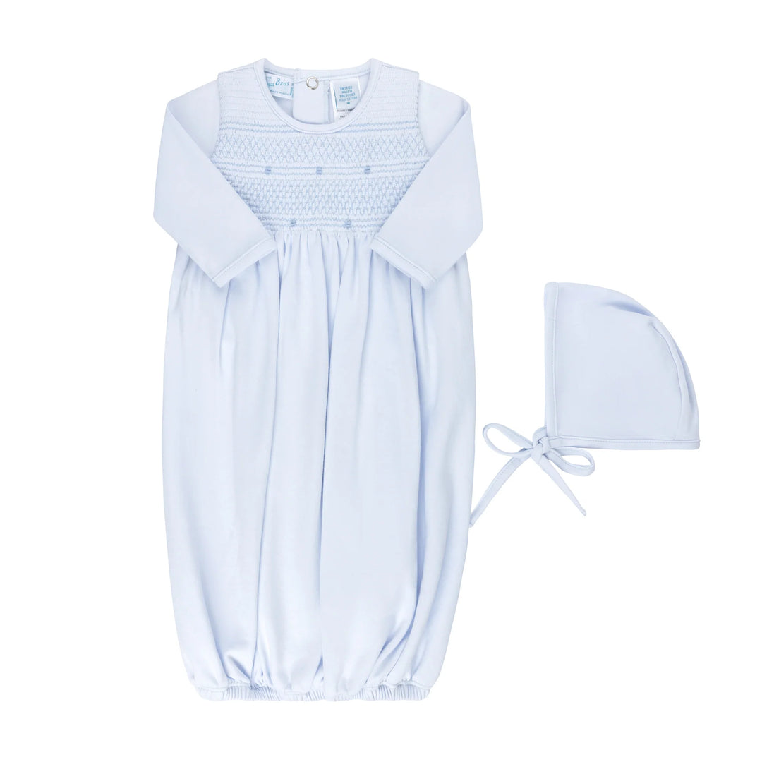 A light blue baby smocked dress with long sleeves and a smocked yoke, shown flat on a white background with a matching bonnet.