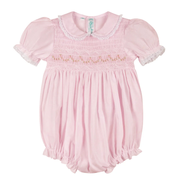 A baby girl's light pink smocked bubble romper with short puff sleeves, white lace trim, and a Peter Pan collar, shown flat on a white background.