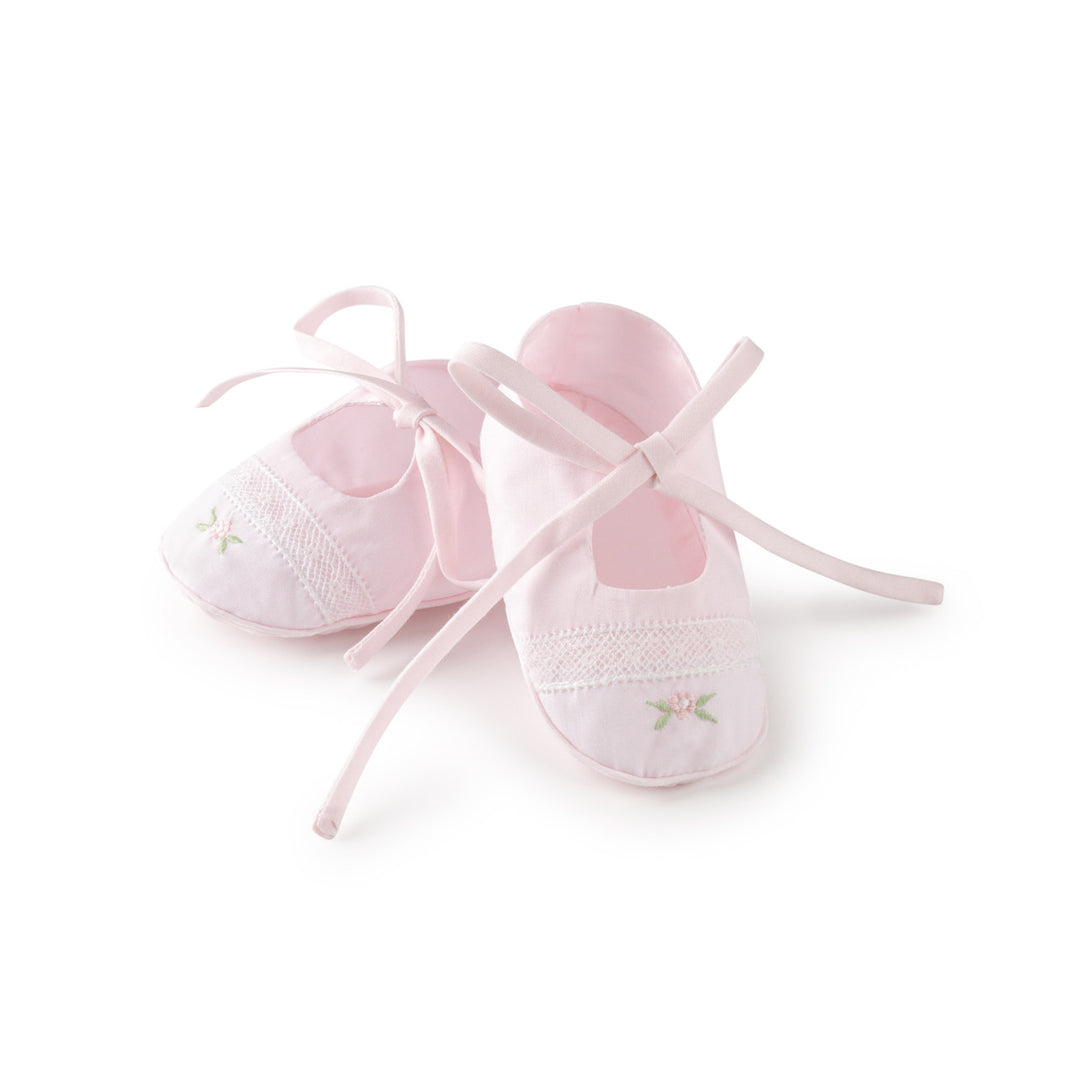 A pair of light pink baby ballet flats with delicate lace trim and small embroidered floral details, shown on a clean white background.